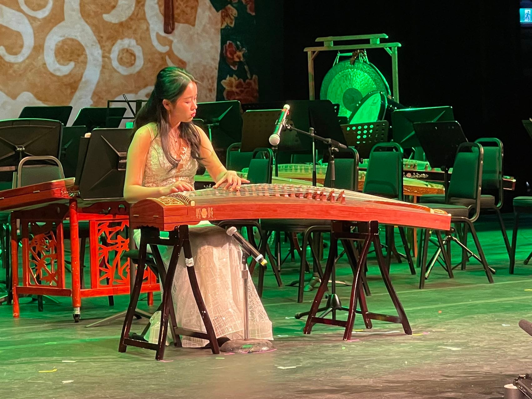 A YCMA guzheng musician performing on an academy stage